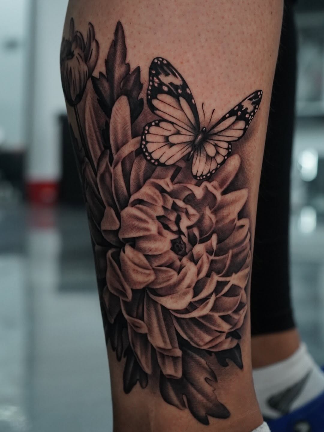 Completed chrysanthemum and butterfly tattoo showcasing garden-inspired design work