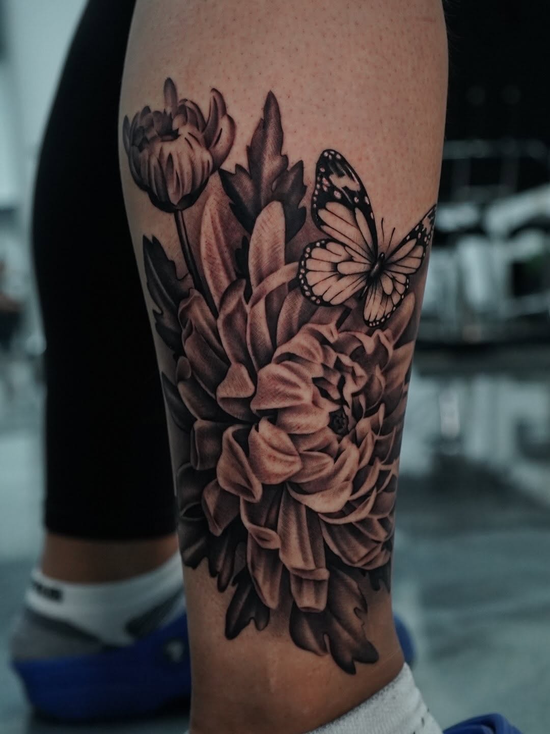 Floral tattoo featuring chrysanthemum bloom and butterfly at Midtown Sacramento shop